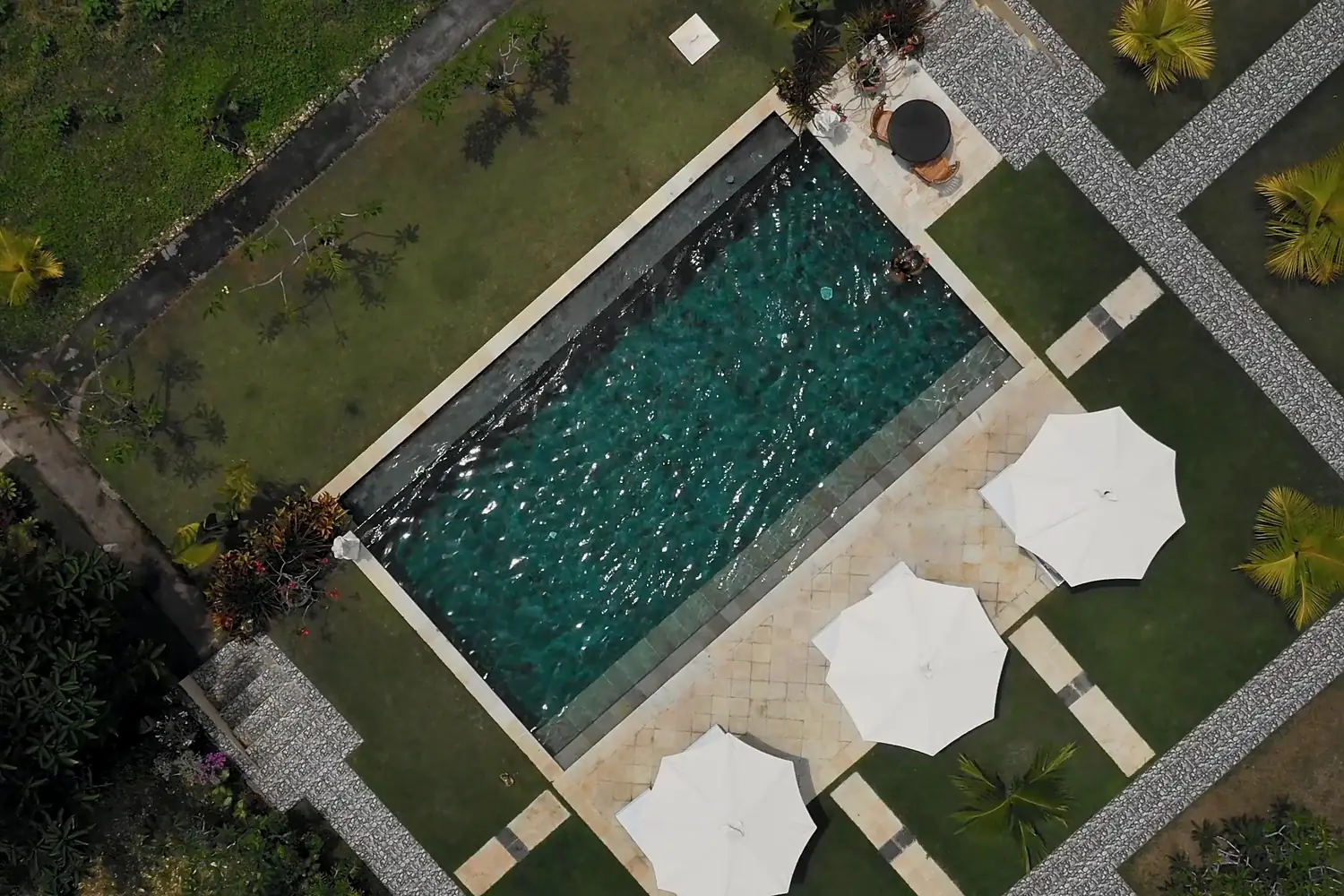 Le jardin entier vu de haut : le bassin, la plage, les parasols et les allées